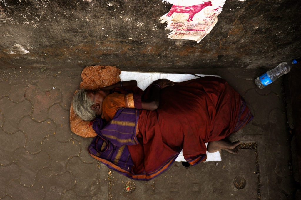 Photo of an elderly woman sleeping on the pavement in Mumbai, India.