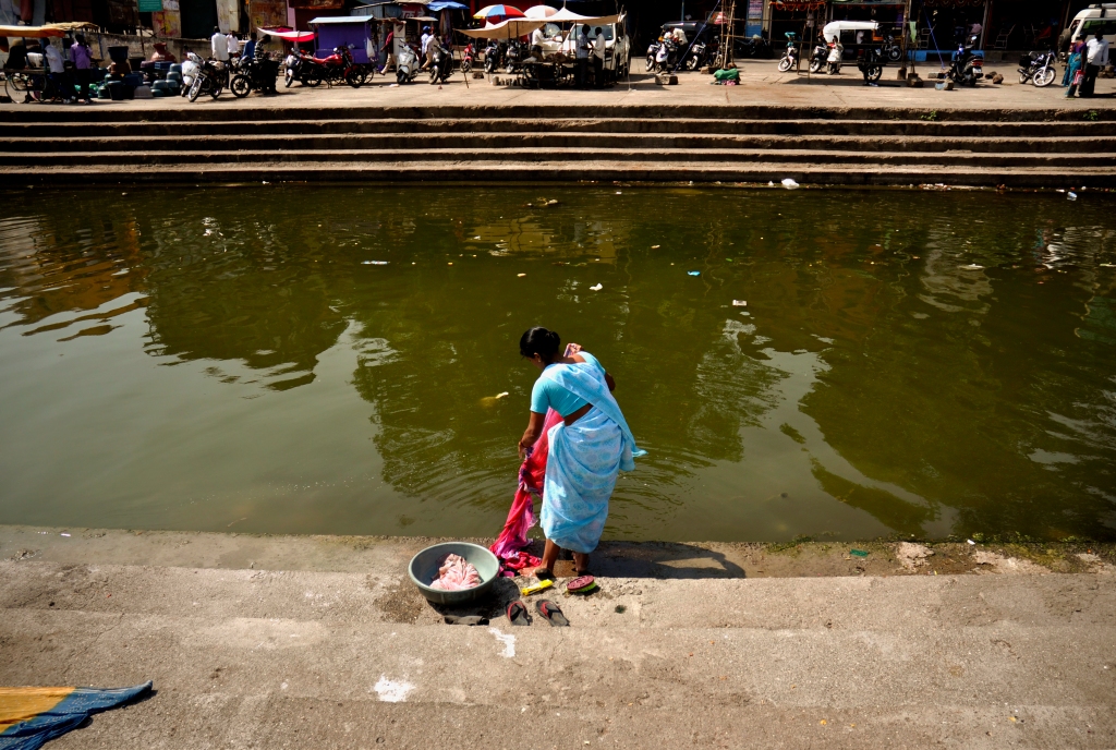 Photo of a woman doing the laundry in a river in India.