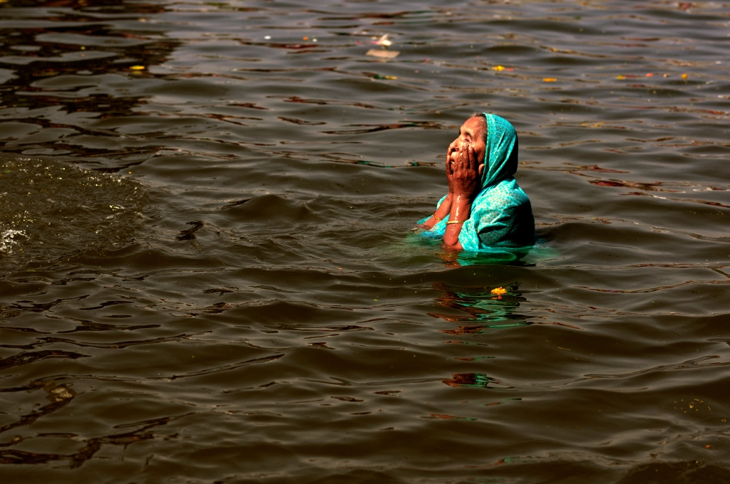 Photo of a woman bathing in the Ramkund Pond in Nashik in India.