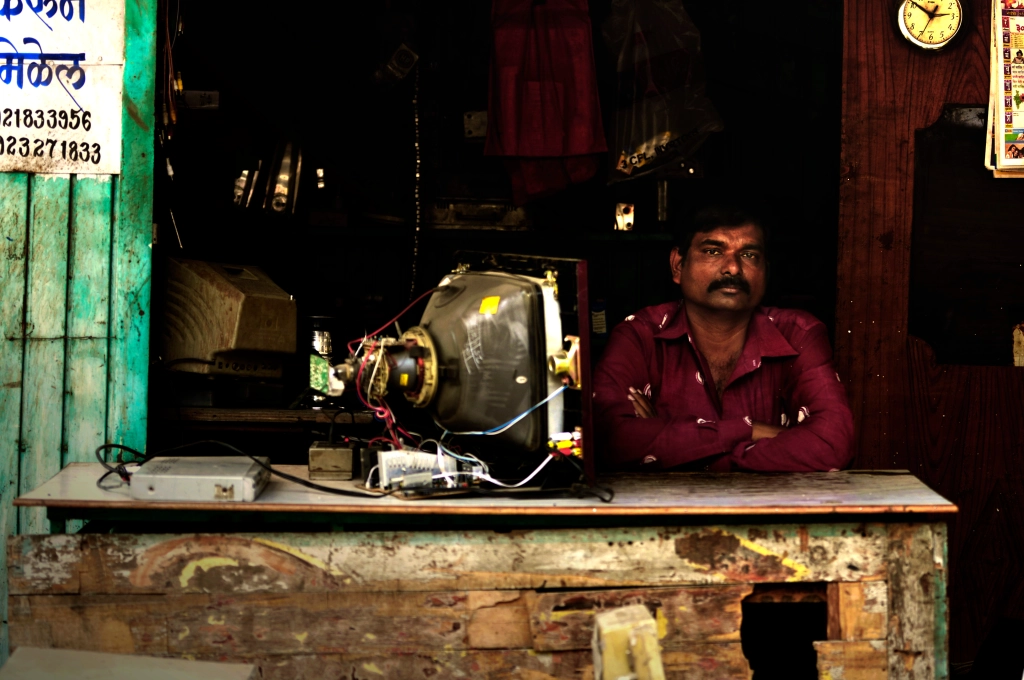 Photo of an Indian man in a television repair shop, India.